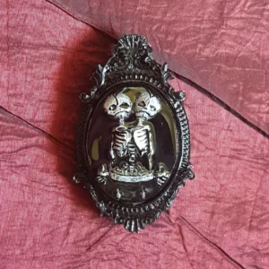 Cette broche style camée gothique avec squelette siamois sera parfaite pour accessoiriser une robe, un pull ou même un sac. Les seules limites sont celles de votre imagination!