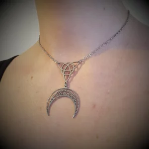 Ce collier ras du cou est orné d'une triquetra qui soutient un croissant de lune, le tout en acier inoxydable. Finesse et délicatesse sont les maîtres mots de cet élégant bijou.