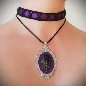 Ce collier ras de cou rose noire baroque vous enchantera avec son grand médaillon gothique style portrait et sa délicate partie ras de cou, mêlant dentelle géométrique et satin violet.