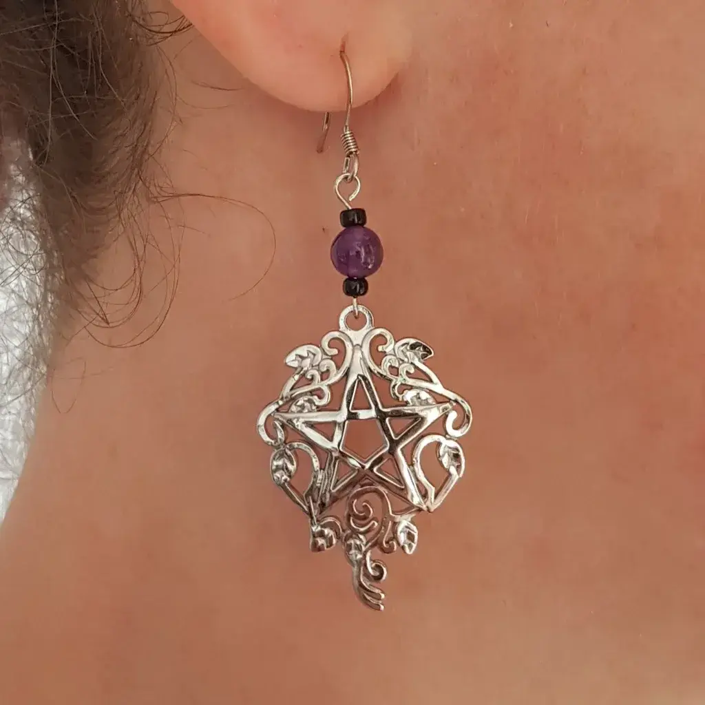 Acier inoxydable et améthyste, pierre et métal, voila un ensemble avec une touche de couleur pour ces boucles d'oreilles pentagramme witchy. Et une pointe de verre noir pour faire ressortir le tout!