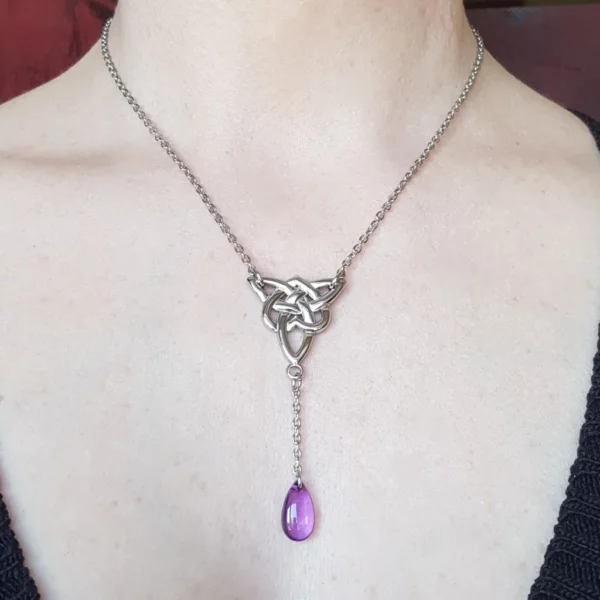 Ce collier triquetra celtique et perle goutte en verre violette sera du plus bel effet pour finir votre look tout en élégance. En acier inoxydable et verre.