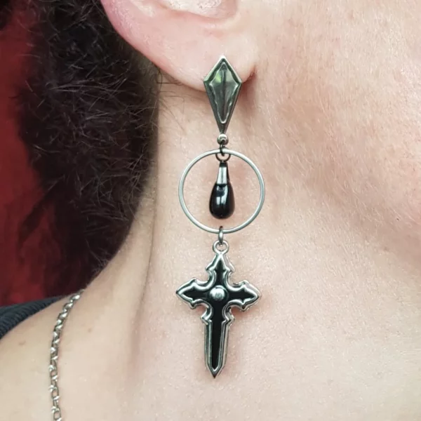 Ces boucles d'oreilles croix gothique en acier inoxydable sont accompagnés d'une perle goutte en verre noir, réhaussant l'ensemble harmonieusement. Et avec la jolie longueur de leurs pendants, impossible que ces bijoux noir et acier passent inaperçus!
