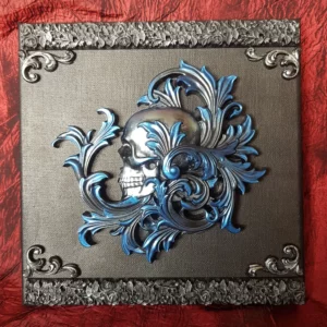 Cette décoration murale tête de mort baroque, dans les tons bleu et argent, ravira au plus haut point les fans d'arabesques baroque et de crâne.