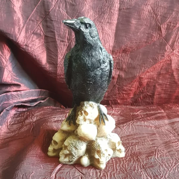 Cette statuette gothique le corbeau du cimetierre sera parfaite pour finir votre décoration d'autel ou tout autre endroit à votre convenance. Perché sur ses têtes de mort empilés, la sombre créature scrutera élégamment les alentours tout en veillant sur son trésor.