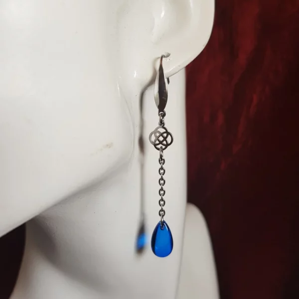 Ces boucles d'oreilles celtique avec perles rouge ou bleu se distinguent par leur finesse et leur long pendant avec finition perle goutte en verre transparent.