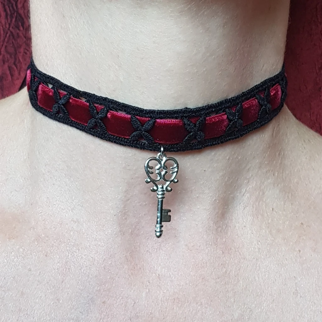 Ce collier tour de cou baroque clef des secrets se compose d'un choker en dentelle noire et velours rouge, orné d'un pendentif clé en acier inoxydable.